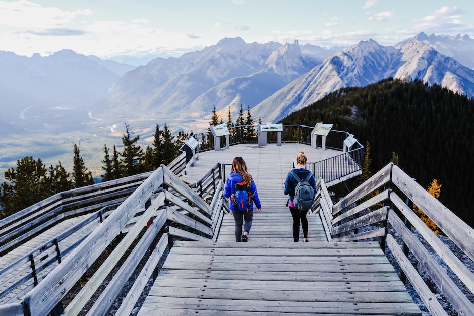 A group of backpackers standing on a mountaintop, enjoying the view and smiling.