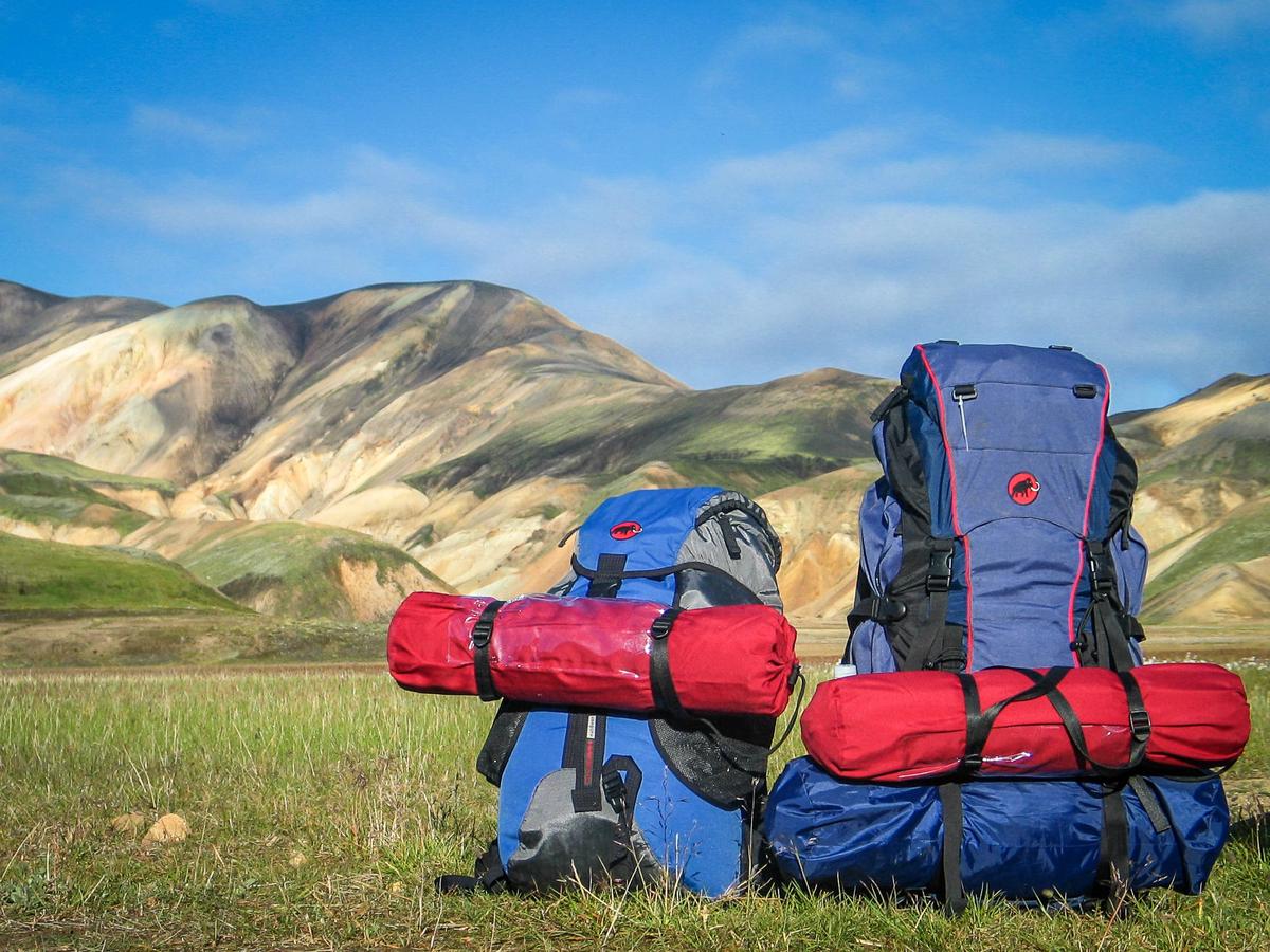 A person backpacking with a map, representing budget travel planning for exploring the world.