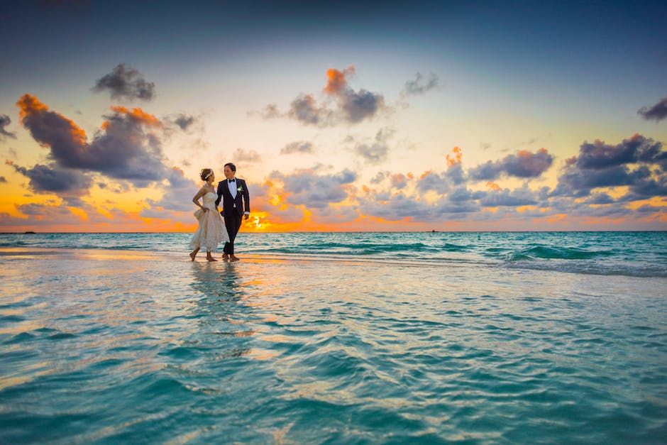 A couple standing on a beautiful beach during sunset, symbolizing a dream honeymoon getaway